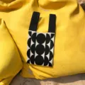 Schwarze und weiße geometrische Strickhandtasche Detail mit Griffen auf gelbem Hintergrund. - Handtasche Stil / Schwarz