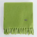 Primer plano detalle de bufanda de invierno tejida verde suave con flecos, cálida. - Verde amarillento