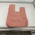Rosa japanischer Knotenbeutel Detailansicht, weicher Satinstoff mit kompaktem Handgelenkdesign. - Pfirsich