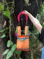 Close-up detail of knitted tote bag with bright orange fabric, pink handle and teal chain link. - Handle Set Style / Orange