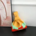Detailansicht einer modischen Strick-Knoten-Handtasche im trendigen Farbblock-Design. - Gelb