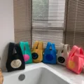 Detailaufnahme süßer Strick-Tragetaschen mit Smiley-Motiven, ordentlich auf einer Fensterbank. - Schwarz