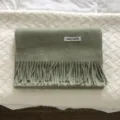 Vista detallada de bufanda suave de lana con flecos en verde liso con etiqueta 100% lana. - Verde Frijol Mungo