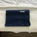 Vista detallada de una bufanda de invierno de lana azul oscura lisa con flecos y etiqueta. - Azul marino