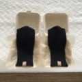 Primo piano dettagliato di guanti lavorati a maglia nera presentati in scatole di carta. - Nero / 23x9cm
