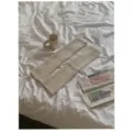 Gedetailleerd shot van beige gebreide beenwarmers op wit laken met mok en krant. - Ivoor