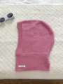 Gros plan détaillé d'un bonnet cagoule en laine tricotée rose doux avec étiquette 100% laine. - Rose