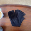 Gants tricotés noirs sans doigts détail, manchettes douillettes sur table en bois. - 40x10cm / Noir