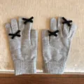 Nahaufnahme Detail der süßen grauen Strickhandschuhe mit eleganten schwarzen Schleifen. - 21x11cm-U203S / Grau