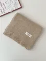 Detailansicht eines kuscheligen khakifarbenen Strickschals, ordentlich gefaltet mit Etikett. - 170x22cm / Gebrochenes Weiß