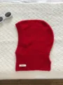 Detail shot of bright red woolen balaclava knitted fabric and 100% wool label texture. - Red