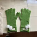 Detailansicht winterlicher grüner Strickhandschuhe mit weißen Bommeln und gerippten Bündchen. - Einheitsgröße / 24x10cm / Grün