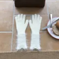 Nahaufnahme eleganter cremeweisser Strickhandschuhe mit flauschigen Bündchen und kleinen Labeln. - Einheitsgröße (W313) / Elfenbein