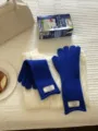 Nahaufnahme von blauen Winter-Strick-Touchscreen-Handschuhen auf weißer Strickjacke. - Blau