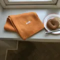 Detaillierte Nahaufnahme eines kuscheligen orangefarbenen Strickschals auf der Fensterbank. - 160x21cm / Orange