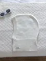 Gros plan de la cagoule tricotée blanche en laine, bonnet d'hiver douillet à plat. - Blanc