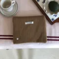 Nahaufnahme der braunen Strickschal-Textur mit handgefertigtem Etikett und gemütlichem Styling. - 156X22CM / Camel