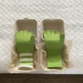 Grüne Strick-Touchscreen-Händeschuhe kreativ in Takeaway-Boxen präsentiert, Detailansicht. - Buchstabe F / Gelbgrün