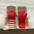 Nahaufnahme niedlicher roter und gestreifter Strick-Touchscreen-Handschuhe in Boxen. - Buchstabe F / Rot