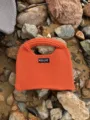 Nahaufnahme Detail der leuchtend orangefarbenen Stricktasche mit strukturierter Handtasche. - Orangerot