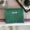 Detailansicht des grünen Wollmischgewebe-Strickschals mit handgefertigtem Etikett. - 156X22CM / Hellgrün