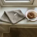 Nahaufnahme des kuscheligen Winterschal in beiger Strickoptik mit handgemachtem Etikett. - 160x21cm / Khaki