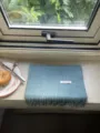 Detail view of solid blue winter wool scarf with tassel ends and 100% wool label on windowsill. - Lake Blue