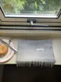 Detail shot of grey wool scarf fringe and 100% wool label on natural windowsill. - Light Gray