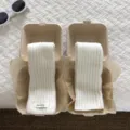Detail view of cozy white wool knit arm warmers presented in creative eco paper boxes. - White