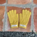 Nahaufnahme von einfarbigen gelben Strick-Touchscreen-Handschuhen mit Markenetikett am Bündchen. - 21x11cm-H005S / Gelb
