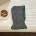 Detailed view of the cozy grey knit balaclava with contrast green trim, winter hood scarf combo. - Gray