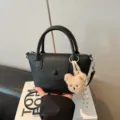 Chic black textured leather top handle crossbody bag featuring a cute fluffy bear pendant. - With Pendant / Black