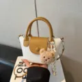 Stylish women's handbag with contrast color, top handle and crossbody strap for daily wear. - With Pendant / White