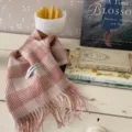 Nahaufnahme eines weichen rosa karierten Wollschals mit fransen und Qualitätslabel. - Altrosa