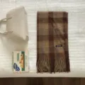 Klassisches braunes Karoschal-Detail mit Fransenrand und gewebtem Markenetikett. - Braunes Karomuster