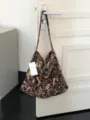 Detailansicht der vintage floralen Canvas-Schultertasche hängend an einer weißen Tür. - 57x44cm / Kaffeebraun