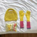 Detailed view of yellow knit handbag and color-blocked arm warmer gloves on white bedding. - 39x10cm / Pink