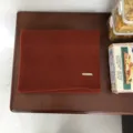 Detaillierte Ansicht eines warmen rostbraunen Strickschals mit elegantem Metalllabel. - 160x30cm / Orange