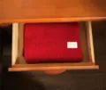 Detailansicht eines roten Strickschals, ordentlich in einer Holzschublade verstaut für Winter. - Rot