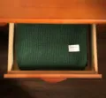 Detaillierte Nahaufnahme des dunkelgrünen Strickschals, ordentlich in Holzschublade. - Grün