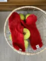 Detaillierte Nahaufnahme roter Plüsch-Winterhandschuhe in einem Drahtkorb mit grünen Äpfeln. - Vollfinger / 27x10cm / Rot