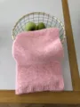 Nahaufnahme der soften pinken Strickschal Textur, dekoriert im Korb mit frischen Äpfeln. - Rosa