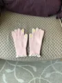 Close-up detail of pink winter knitted touchscreen gloves with cute white ruffle cuffs. - Pink