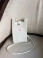 Detalle de mini bolso bandolera de punto, cartera beige con botón de presión y etiqueta frontal. - Marfil