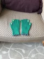 Close-up of green knit touchscreen gloves featuring cute floral fingertips and ruffled cuffs. - Green