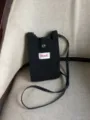 Vista detallada del mini bolso bandolera de punto negro para teléfono, con correa y botón a presión. - Negro