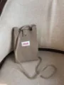 Nahaufnahme der stilvollen gestrickten Mini-Umhängetasche für Handys mit Druckknopf in Khaki. - Khaki