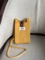 Vista detallada del bolso cruzado de punto amarillo para teléfono con correa de botón a presión. - Amarillo