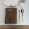 Detailansicht eines kuscheligen einfarbigen Strickschals mit stilvollem gewebten Etikett. - Mokka