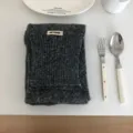 Dunkelgrauer Strickschal Detailansicht, kuschelig texturierter Wollstoff mit Webetikett. - Grau